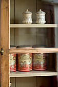 Storage tins and chinaware in glass fronted kitchen dresser in Devon