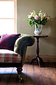 Cut flowers on wood side table with Chesterfield sofa in Devon home