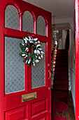Open front door with Christmas garland in London home UK