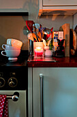 Stacked teacups and utensils on kitchen worktop in London home UK