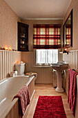 Spotted towels wiith checked roman blinds in bathroom of London home UK