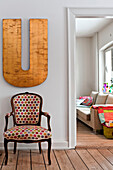 Upholstered amchair under oversized letter U in hallway of modern Odense family home Denmark