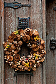 Weihnachtskranz aus Trockenblumen an der hölzernen Eingangstür eines Hauses in Cheltenham, Gloucestershire, England