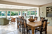 Wooden dining table and chairs in open plan flagstone kitchen conservatory in Canterbury home England UK