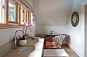 Orchid on double basin with polished brass freestanding bath in Canterbury home England UK