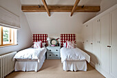 Rot und weiß karierte Kopfteile in einem Zweibettzimmer mit Balken in einem Haus in Canterbury, England, UK