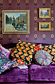 Verschiedene bunte Kissen auf einem lila Sofa unter einem Kunstwerk in einem Londoner Haus (UK)