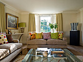 Assorted cushions on sofas in drawing room with bay window in West London townhouse England UK
