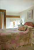 Pink patchwork quilt cover on double bed in rural Suffolk home England UK