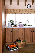 Basket and crate with wooden fitted sink units in rural Suffolk home England UK