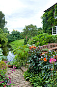 Backsteinpfad und Fußgängerbrücke im Garten eines Landhauses in Suffolk, England UK