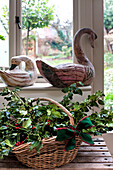 Basket of holly and bird ornaments at window of Walberton home, West Sussex, England, UK