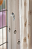 Four glass baubles hang in window of Forest Row family home, Sussex, England, UK