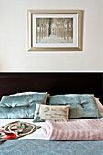 Buttoned light blue pillows on bed below artwork in Paris apartment, France
