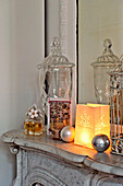 Lit candle and homeware on marble fireplace in Paris apartment, France