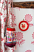 Bestickte Tasche mit Zierteller und gemusterter Tapete und Vorhang in einem Haus in Hertfordshire, England, Vereinigtes Königreich
