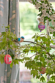 Artificial bird with hand-painted Easter eggs in spring blossom, Essex home, England, UK