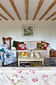 Patchwork-Kissen auf Sofa mit Harfe im Wohnzimmer mit Balken in einem Haus in Essex, England, UK