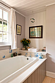 Schnittblumen und Ornamente mit Kunstwerken im Badezimmer mit Nut und Feder in einem Haus in Essex, England, Vereinigtes Königreich