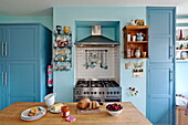 Brot und Kirschen auf Arbeitsplatte in blauer Küche mit Wandregalen in einem Einfamilienhaus in Bovey Tracey, Devon, England, UK