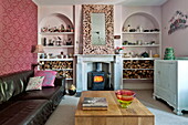 Schwarzes Ledersofa mit hölzernem Couchtisch in einem Wohnzimmer mit rosafarbenen Rundbögen in einem Familienhaus in Bovey Tracey, Devon, England, UK