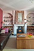 Black leather sofa with wooden coffee table in living room with pink recessed arches in Bovey Tracey family home, Devon, England, UK