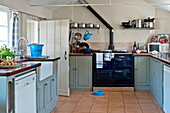 Türkisfarbene Schränke mit marineblauem Herd in der Küche eines Bauernhauses in Suffolk, England, UK