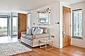 Two seater sofa below ornate white mirror in living room of Wadebridge home, Cornwall, England, UK