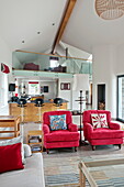 Passende Sessel in offenem, doppelhohem Wohnzimmer eines modernen Hauses, Cornwall, England, UK