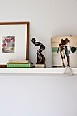 Figurine and books on shelf in bedroom of contemporary home, Cornwall, England, UK