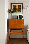 Vintage wooden side cabinet and artwork in living rom of Padstow cottage, Cornwall, England, UK