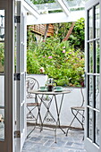 Coffee pot and cups on metal table with chairs on patio of Padstow cottage, Cornwall, England, UK