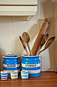 Wooden kitchen utensils in blue and white striped utensil holder, Padstow cottage, Cornwall, England, UK