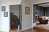 Wine bottles in storage and brown leather armchair in living room with parquet flooring, London home, England, UK