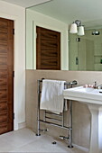 Wash basin and towel rack below mirror in bathroom of London home, England, UK