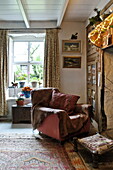 Sessel am Kamin im Wohnzimmer eines Bauernhauses, Cornwall, England, UK