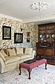 Artwork above sofa in living room with patterned wallpaper, contemporary Suffolk country house, England, UK