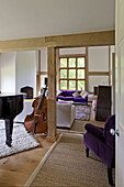 Violette Polstermöbel und Cello im offenen Wohnzimmer eines modernen Hauses in Suffolk/Essex, England, UK
