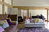 Kontrastierende Sofas mit blumengemustertem Teppich im offenen Wohnzimmer eines modernen Hauses in Suffolk/Essex, England, UK