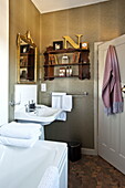 Gilt framed mirror above washbasin with wooden shelving in bathroom of Bury St Edmunds country home, Suffolk, England, UK