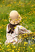 Frau sitzend mit Hahnenfußkette (Ranunculus) Hut in Brecon, Powys, Wales, UK