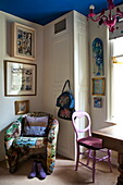 Gepolsterter Stuhl und Taschen mit Kunstwerken in einer Ecke eines Londoner Hauses, England, UK