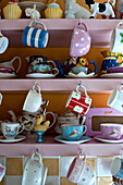 Teacups hanging in kitchen dresser, London home, England, UK