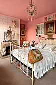 Messingbett und Kunstwerke im rosa Schlafzimmer eines Londoner Hauses, England, UK