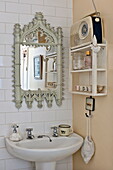 Radio on wall mounted shelf above washbasin in tiled bathroom of London home, England, UK
