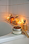 Beleuchtete Kerzen und Badeöle im weiß gefliesten Badezimmer eines Cottage in Shropshire, England, UK