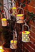 Lit candles hang on plant at brick exterior of Shropshire cottage, England, UK