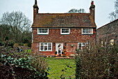 Mid adult woman leaving detached Shropshire cottage, England, UK