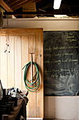 Garden fork and hose with blackboard in shed interior, Blagdon, Somerset, England, UK