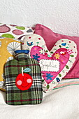 Heart shaped cushion with single word 'Sophie' and hot water bottle on bed in Penzance cottage Cornwall England UK